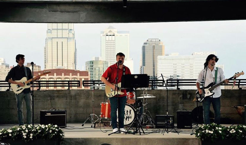 Three members of a band stand on stage and play
